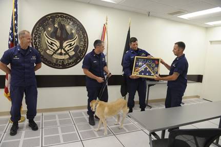 Coast Guard Senior Chief Petty Officer Tin is awarded a traditional shadowbox of keepsake memorabilia at a ceremony held by the Maritime Security Response Team in Chesapeake, Virginia, May 2, 2019. Tin’s retirement ceremony was held in honor of his eight years of service as an explosive detection canine for the Coast Guard. (U.S. Coast Guard photo by Petty Officer 2nd Class Katie Lipe)